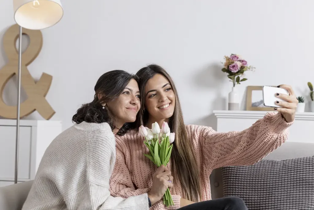 Daughter giving flowers and taking picture with her mother to celebrate Mother's Day