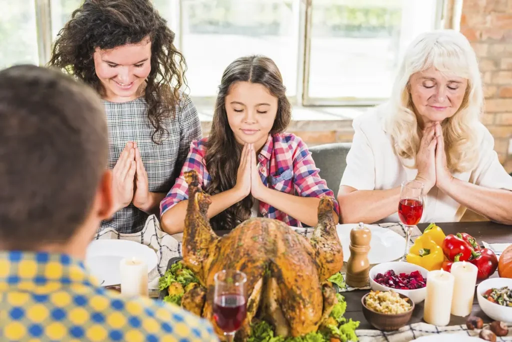 Woman, child and aged lady praying at table on thanksgiving day